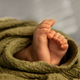 Closeup of newborn baby feet in a green wrap at natural light, indoor photography - PhotoDune Item for Sale