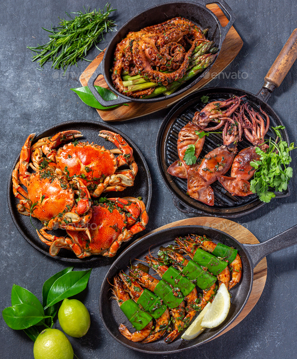 Set of Seafood Dishes. Crabs, octopus, squids and tiger shrimps on cast iron pans and plates