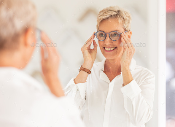 Senior woman, smile and mirror for glasses, vision or eyesight at optometry store. Happy elderly fe
