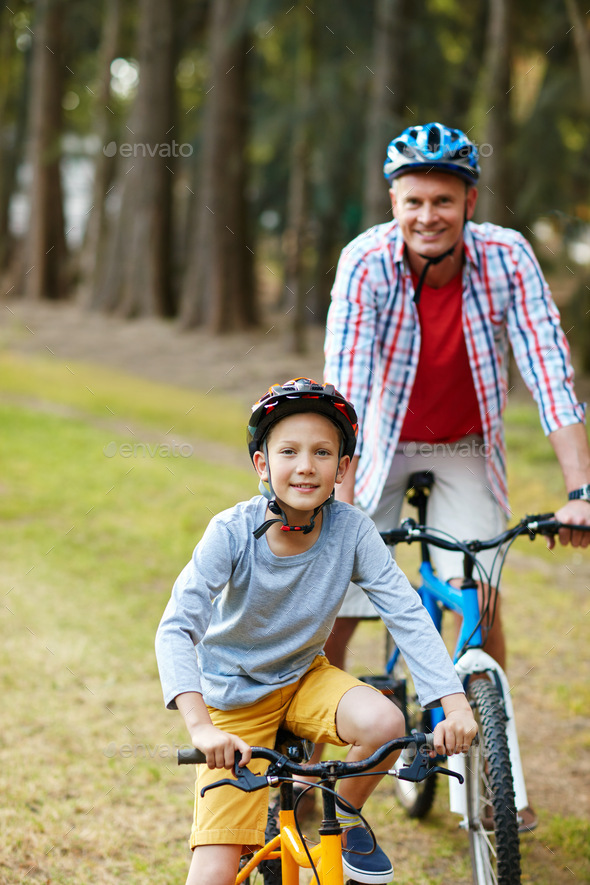 Lets ride. Portrait of a father and son riding bicycles in a park.