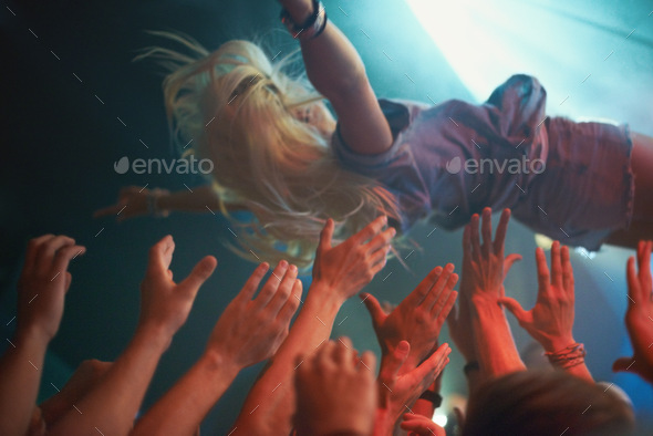 Surfing on a wave of fans. A young woman crowd-surfing at a concert.
