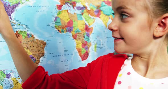 Schoolgirl looking at map in classroom at school alt