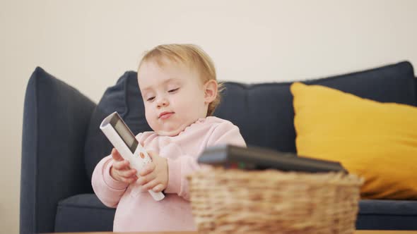 Cute baby playing with a remote control a telephone alt