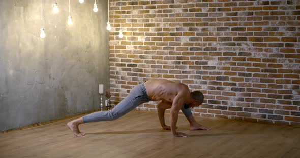 Male Gymnast Is Training Alone in Room, Standing on One Leg and Hand, Holding Body alt