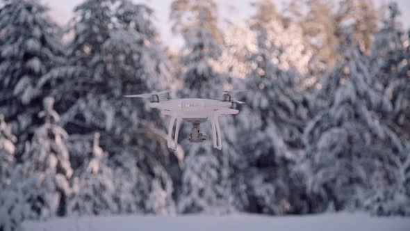 Quadrocopter Unmanned Camera Hovers in Frozen Sky Above Forest 