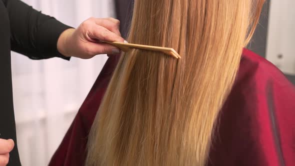 The Hairdresser Combs the Client Blonde Hair with a Comb