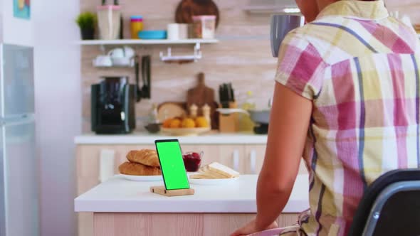 Housewife Looking at Mobile Phone with Green Screen Display alt