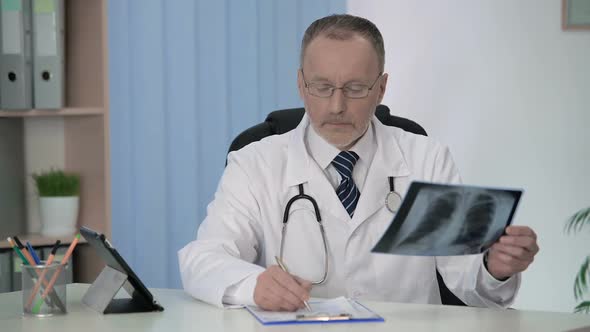 General Practitioner Examining X-Ray, Filling Medical Form for Hospitalization alt