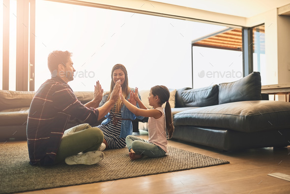 Shot of a happy family of three playing a clapping game together at home