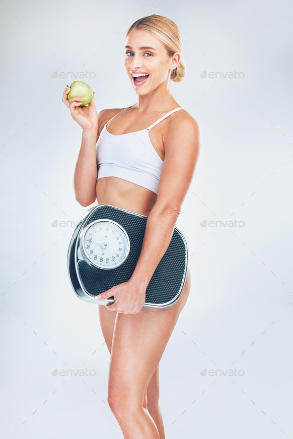 Apple, fitness and woman with a scale for fat loss with a healthy diet after a workout, exercise an