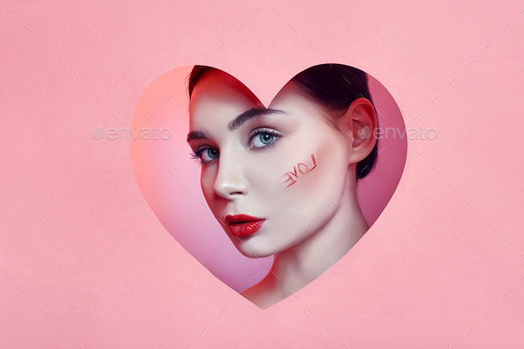 Woman looking in the heart hole, bright beautiful makeup, big eyes and lips, bright lip