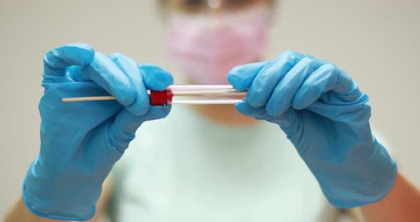 Nurse with facemask holding Coronavirus COVID-19 swab test kit, PPE protective mask and gloves, tube