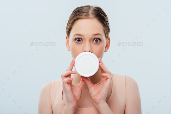 teenage girl with obscure face holding cosmetic cream isolated on grey