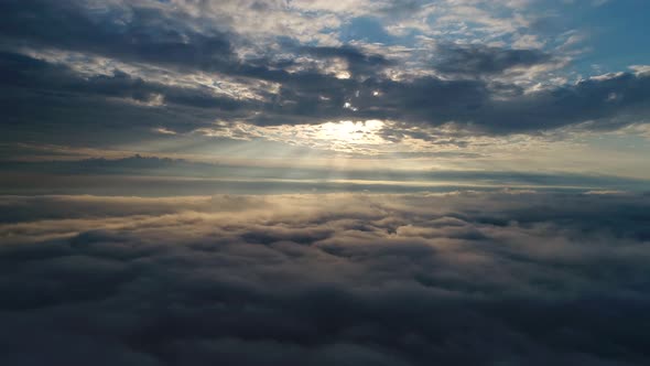 Aerial view, flying above the clouds during sunrise. Scenic view of moving fluffy clouds.