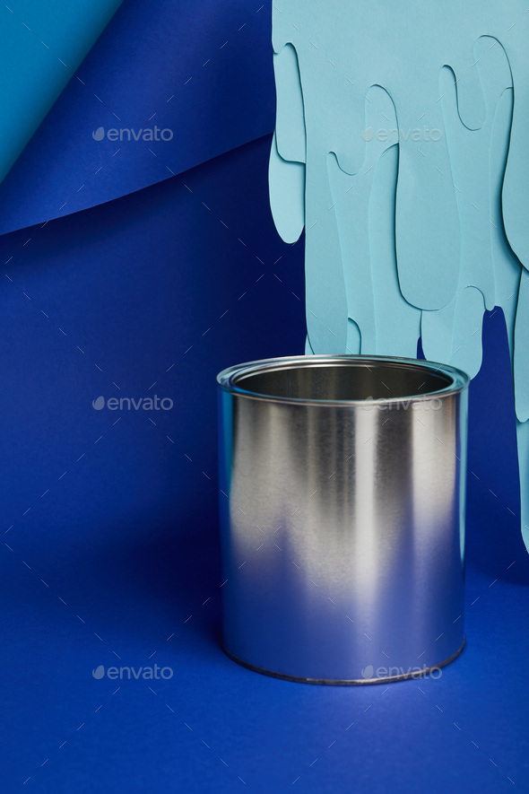 metal shiny can and dripping paper cut paint on bright blue background