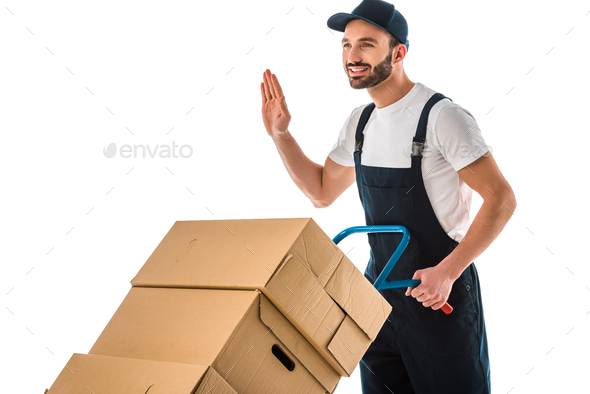 happy delivery man transported cardboard boxes loaded on hand truck and showing hello gesture