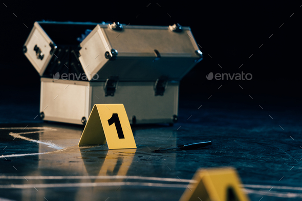 selective focus of knife, investigation kit, chalk outline and evidence markers at crime scene