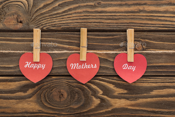top view of clothes pegs and red paper cards with happy mothers day writing on wooden table