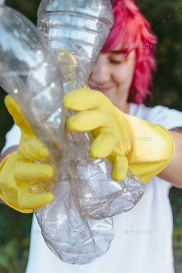 Female wearing gloves holding recyclable plastic bottles plastic