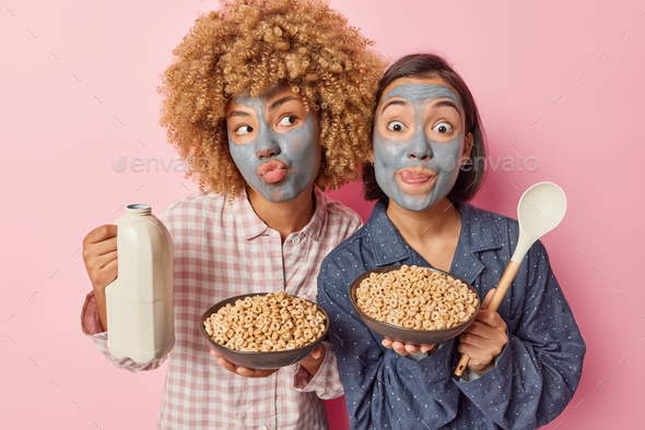 Two women apply beauty facial mask for reducing fine lines going to have tasty healthy breakfast hol