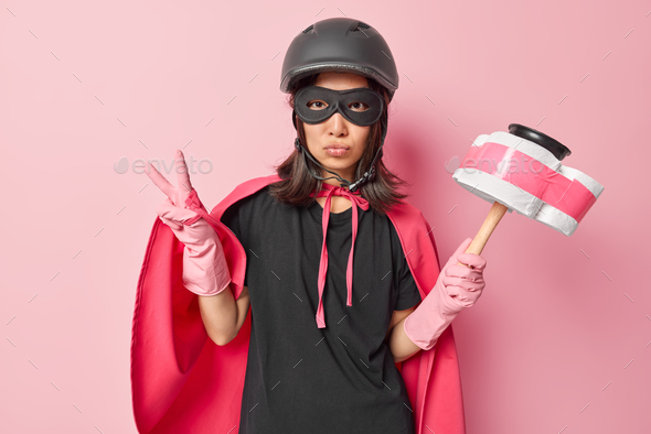 Photo of serious self confident Asian woman superhero holds plunger wrapped with toilet paper makes