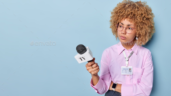 Horizontal shot of serious female journalist records daily tv news holds microphone dressed in forma
