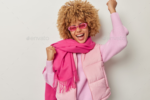Yes I did it. Curly haired overjoyed woman clenches fists raises arms celebrates success exclaims fr