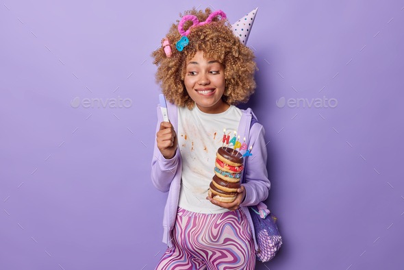 Pregnant curly haired woman holds pregnancy test and delicious doughnuts celebrates birthday wears c