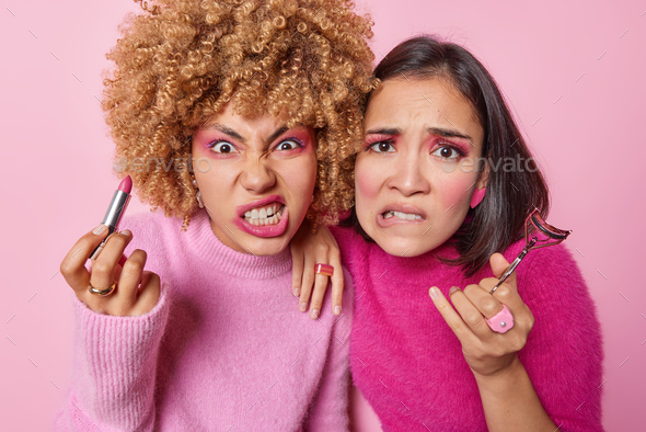 Photo of two irritated female models look angrily cannot apply professional makeup use professional
