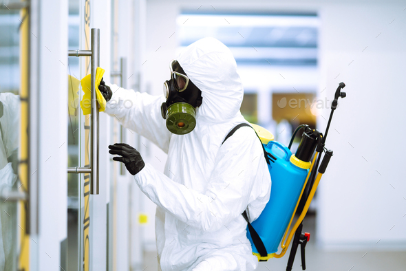 Cleaning and disinfection of office to prevent COVID-19, Man in protective hazmat suit washes office