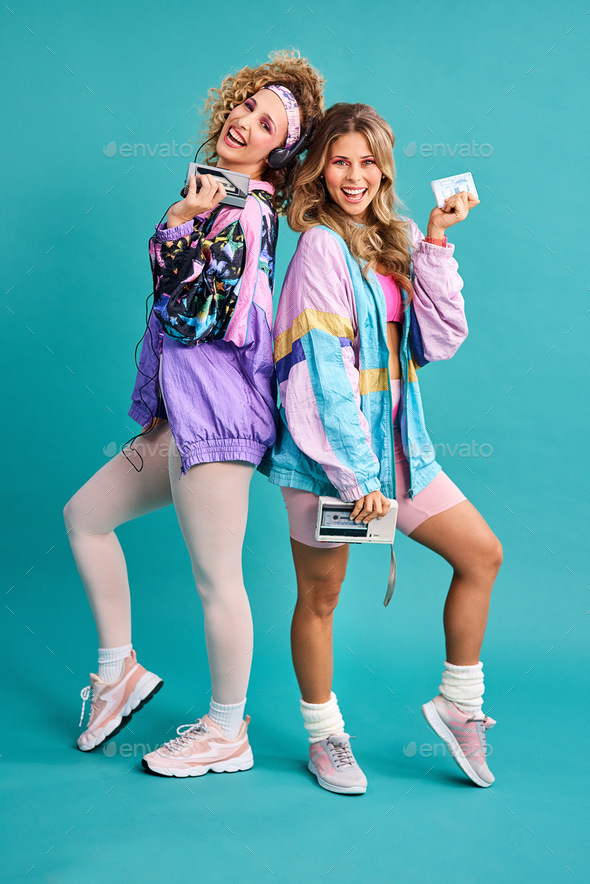 Were out spreading some 80s vibes. Studio shot of two beautiful young women  styled in 80s clothing. Stock Photo by YuriArcursPeopleimages