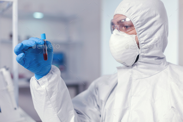 Medical engineer looking at sample of blood in tube