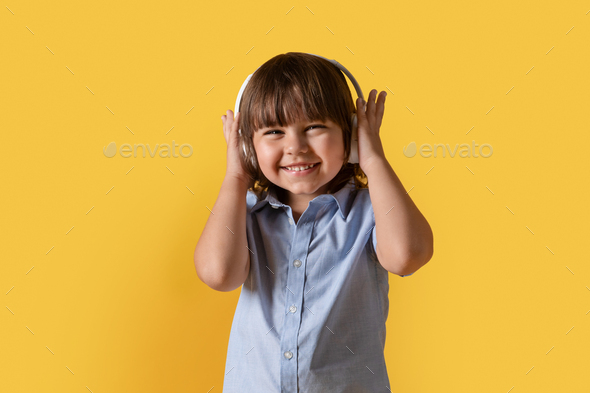 Little music lover. Studio portrait of happy little boy in wireless headphones, enjoying great sound