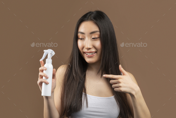 Hairstyle cosmetic concept. Korean lady holding bottle with hair spray, recommending new beauty