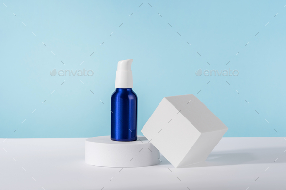 Cosmetic cream metallic pump bottle mockup on blue background with stylish props on white