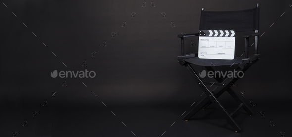 Clapperboard or movie slate with black director chair on black background.