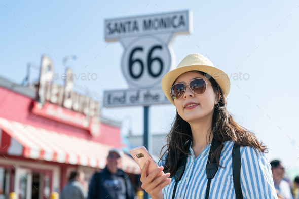 lady using phone by route 66 end of trail sign