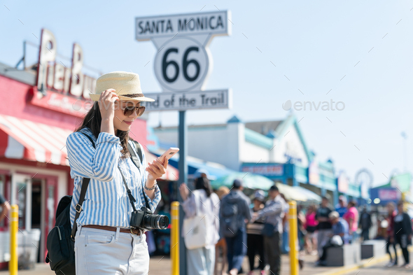 lady looking at phone by end of route 66 sign