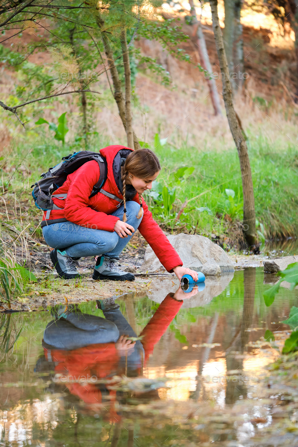 Hiker filling water bottle of raw water in a creek.