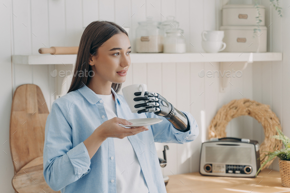 Relaxed disabled girl holds cup of coffee, using bionic prosthetic arm ...