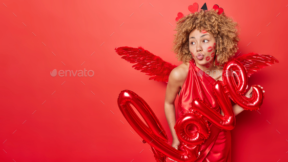 Romantic woman keeps lips rounded poses with inflated letters love dressed  in cupid costume pretends Stock Photo by wayhomestudioo