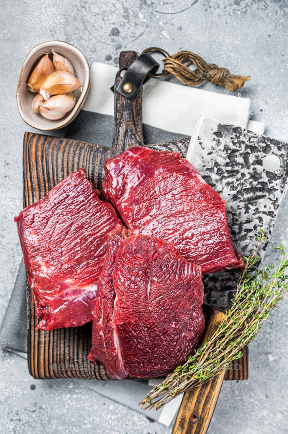 Raw Venison dear meat on butcher cutting board, game meat. Gray background. Top view