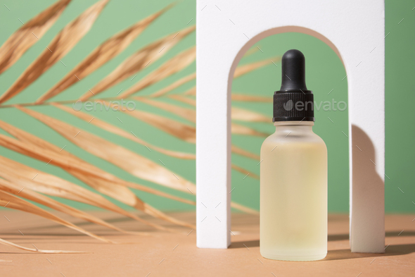 Cosmetic bottle with body and face oil on palm leaf, summer natural cosmetics, serum, facial oil