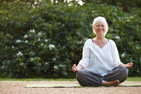 Portrait of an attractive mature woman sitting in the lotus position ...