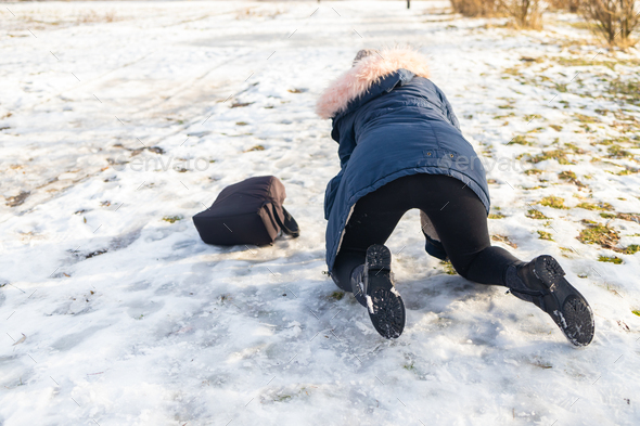 woman slips and falls down on snowy road.
