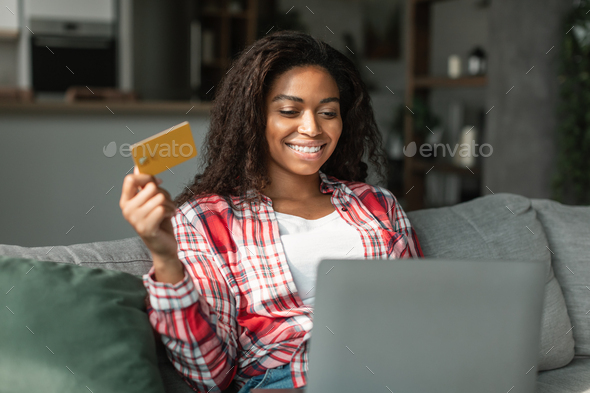 New buy and app for pay. Happy millennial black lady using computer and credit card to check bank