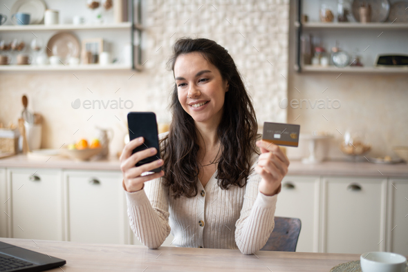 Happy caucasian woman buying food online, using cellphone and plastic credit card, shopping online