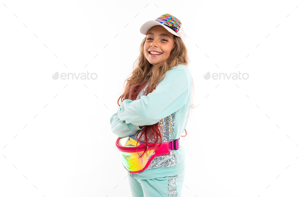 Smiling teenage girl in sparkling clothes, fashionable cap and wearing waist bag isolated