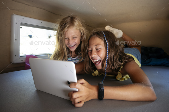 Two sibling boys using the tablet on a wonderful day camping in a van. Van life concept.
