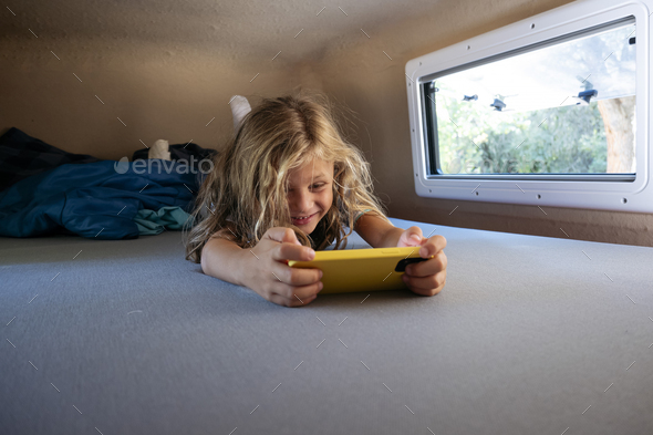 Little boys using the smartphone on a wonderful day camping in a van. Van life concept.